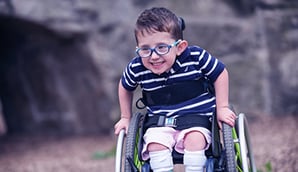 smiling boy rolling in wheelchair